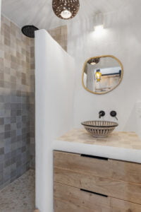 Compact rustic bathroom with round mirror at Casa Aduar 22 Marbella