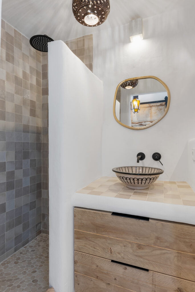 Compact rustic bathroom with round mirror at Casa Aduar 22 Marbella
