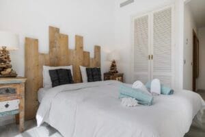 Bright bedroom with white bed and turquoise cushions – Jardín de los Pinos Marbella
