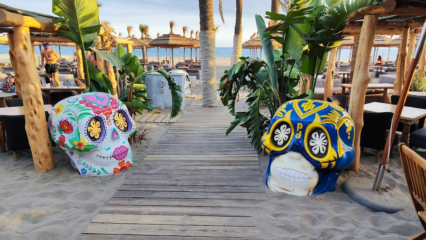 Playa Padre Marbella beach club entrance with colorful skull sculptures and beachfront terrace
